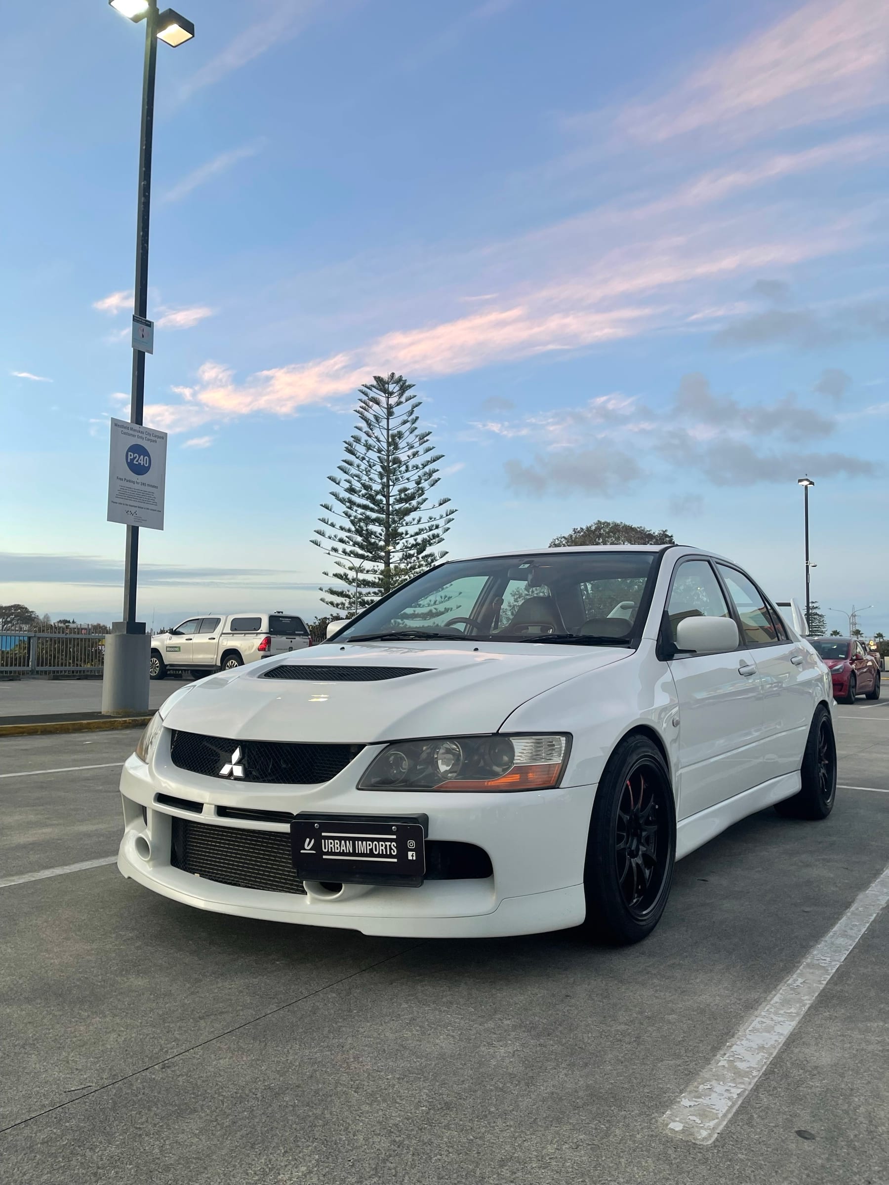 A white Mitsubishi Lancer Evolution IX photographed at sunset